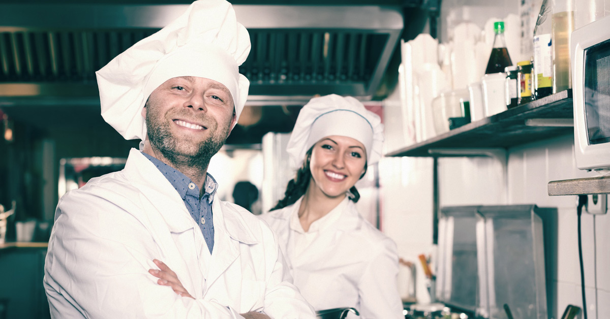 Dos chefs sonrientes posan en la cocina de un restaurante.  