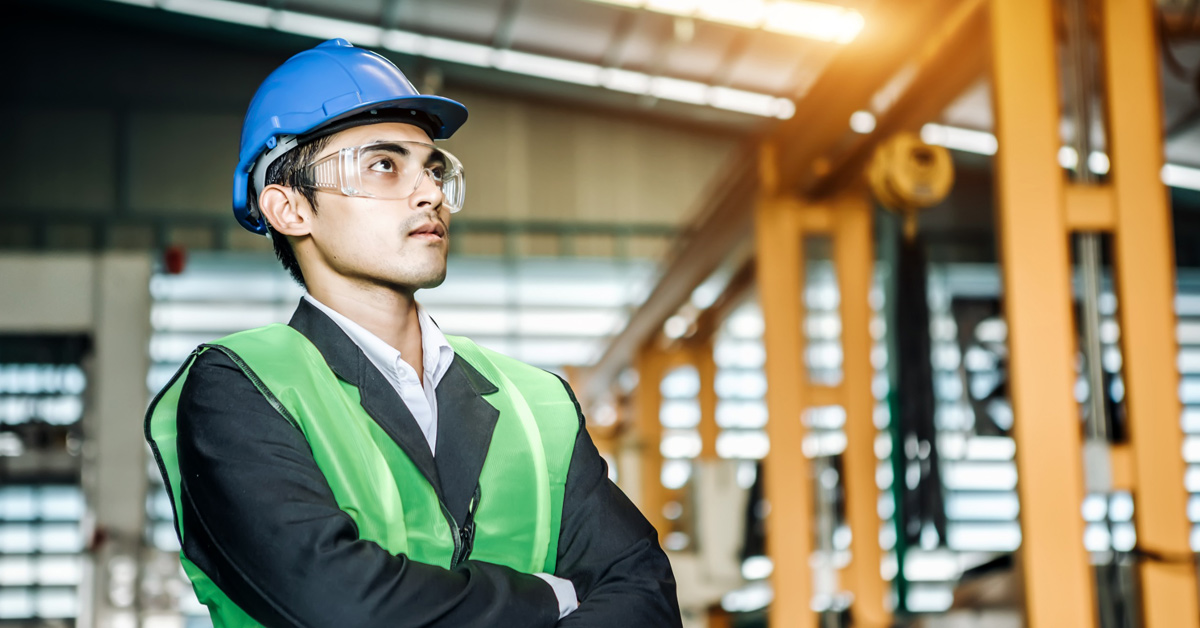 Profesional del sector industrial con casco y gafas de seguridad en el interior de una fábrica