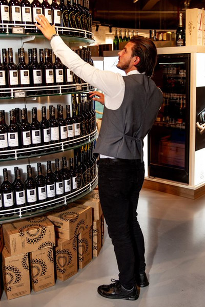 Employé de supermarché montrant la disposition en rayon des bouteilles de vins