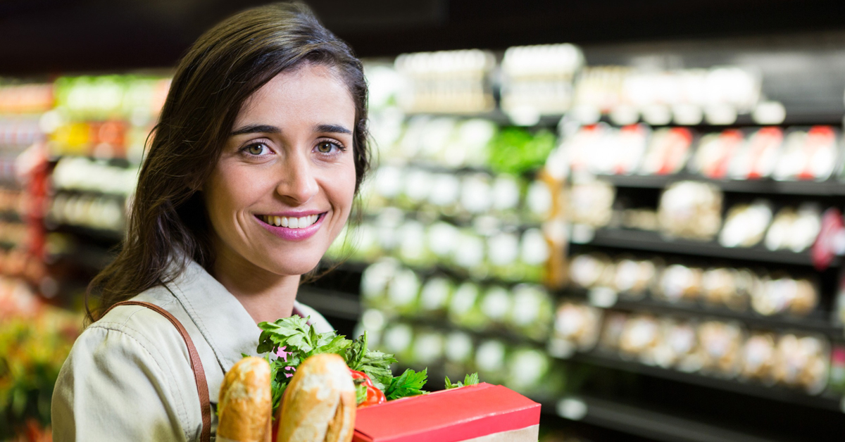 Jeune femme souriante portant un sac de course rempli de produits