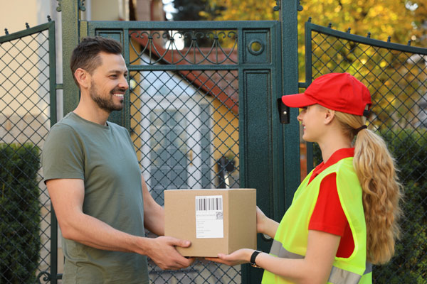 Homme recevant un colis de la part d’une livreuse à pied 