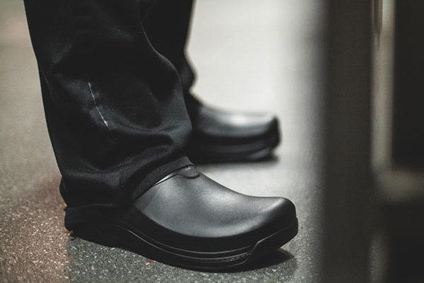 Restaurant worker wearing black non-slip kitchen shoes during his shift