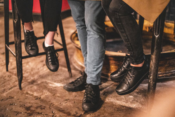 Man bending down on one knee in front of wine stand wearing black, slip-resistant shoes for work