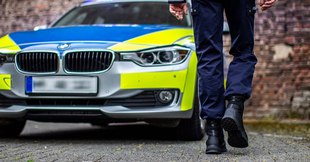 Police officer walking towards squad car wearing black, slip-resistant outdoor work boots