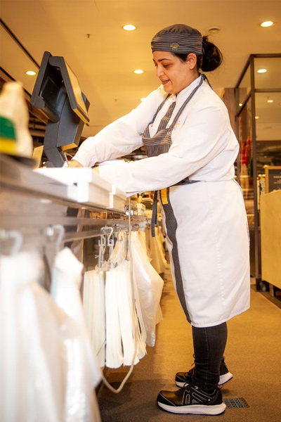 Butcher working behind the meat counter wearing durable black and white work shoes from Shoes For Crews