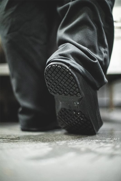 Kitchen worker stepping on the toe of his black slip-resistant shoe to relieve pressure from heel