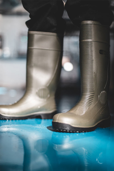 Manufacturing worker standing on wet floor wearing slip-resistant Shoes For Crews work boots