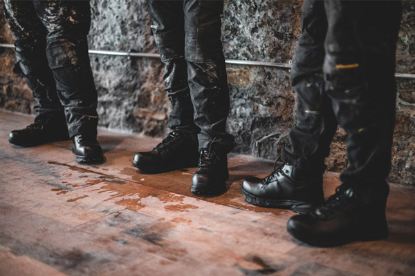 Three facility workers wearing black, slip-resistant safety boots on the job