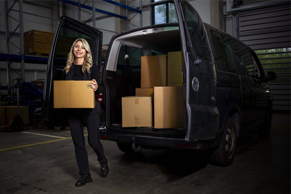 Delivery driver loading black van with boxes in warehouse